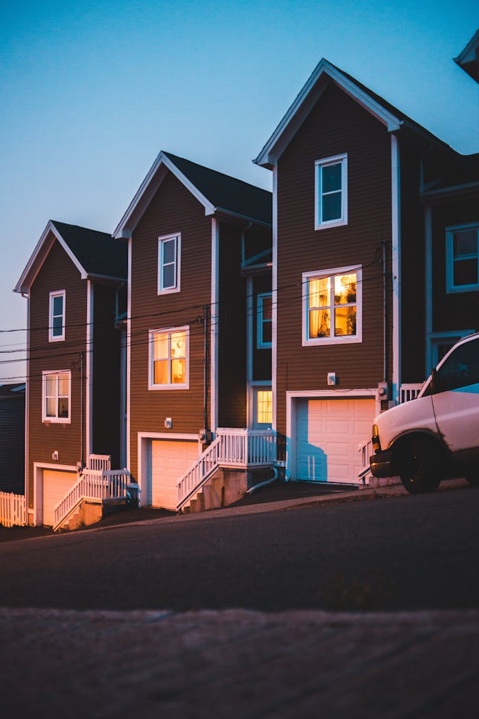portfolio-03 A serene view of modern houses on a sloped street under a twilight sky, exuding warmth and coziness.